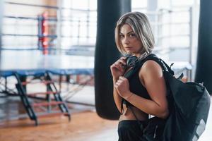 Serious look. Adult female with black bag and headphones in the training gym photo