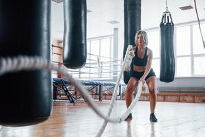 Pushing bags hanging around. Blonde sport woman have exercise with ropes in the gym. Strong female photo
