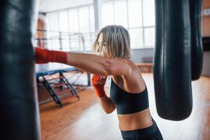 Left hand kick. Female boxer is punching the bag. Blonde have exercise in the gym photo