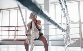 On the boxing ring. Blonde sport woman have exercise with ropes in the gym. Strong female photo