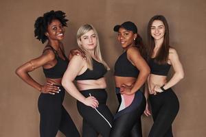 Human bodies. Group of multi ethnic women standing in the studio against brown background photo