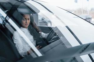 Busy person. Beautiful businesswoman trying her new car in the automobile salon photo
