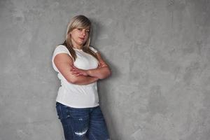 Arms crossed. Young white woman in the studio standing against grey background photo