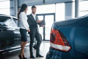 dos personas. cliente femenina y hombre de negocios barbudo con estilo moderno en el salón del automóvil foto