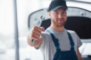 siempre listo para ayudar a su vehículo. empleado en el uniforme de color azul se encuentra en el salón del automóvil foto