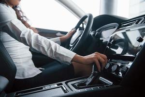 Ring on the finger. Cute girl with black hair trying her brand new expensive car in the automobile salon photo