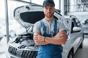 Employee in the blue colored uniform stands in the automobile salon photo