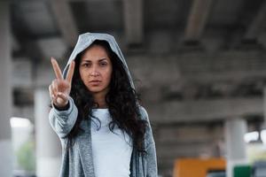 Meaningful gesture. Portrait of beautiful young woman standing under the bridge outdoors photo