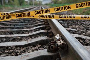 No tocar. peligroso explosivo tirado en el ferrocarril. cinta amarilla de precaución en el frente foto