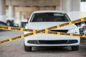 no se permite la entrada ilegal aquí. cinta amarilla de precaución cerca del estacionamiento de autos durante el día. escena del crimen foto