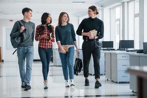 cuatro personas. grupo de jóvenes trabajadores caminando en la oficina en su tiempo de descanso foto