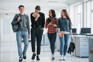 Man is laughing. Group of young people walking in the office at their break time photo