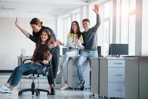 Speed and smiles. Having fun in the office. Young people have a break and driving by using a seat photo