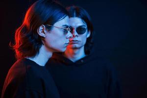 Serious people. Portrait of twin brothers. Studio shot in dark studio with neon light photo