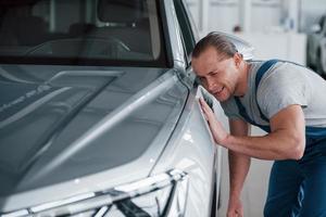 No está mal. después de la reparación profesional. hombre mirando un coche de color plateado perfectamente pulido foto