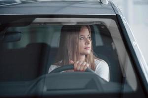 Relaxed look. Girl in modern car in the salon. At daytime indoors. Buying new vehicle photo