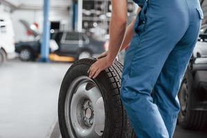 Old tire. Employee in the blue colored uniform works in the automobile salon photo