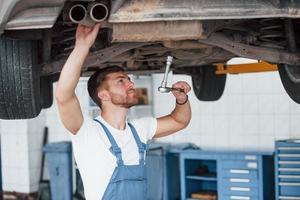 Adjusting the wheels. Employee in the blue colored uniform works in the automobile salon photo