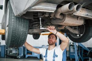 Shock absorbers on photo. Employee in the blue colored uniform works in the automobile salon photo