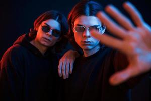 Showing the hand. Portrait of twin brothers. Studio shot in dark studio with neon light photo