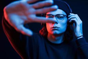 In my own world with music. Studio shot in dark studio with neon light. Portrait of serious man photo