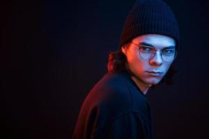 Looking straight at the camera. Studio shot in dark studio with neon light. Portrait of serious man photo