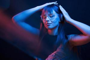 Nice blurring effect. Studio shot in dark studio with neon light. Portrait of young girl