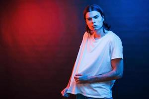 That shirt is not long enough. Studio shot in dark studio with neon light. Portrait of serious man photo