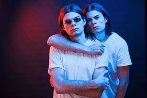 Family photo. Portrait of twin brothers. Studio shot in dark studio with neon light photo