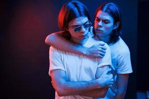 People's unity. Portrait of twin brothers. Studio shot in dark studio with neon light photo