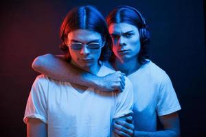 We strong together. Portrait of twin brothers. Studio shot in dark studio with neon light photo