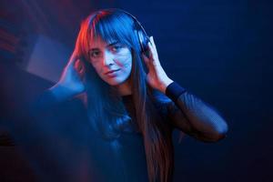 Good mood for all. Studio shot in dark studio with neon light. Portrait of young girl photo