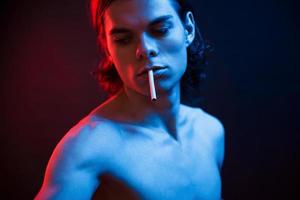 Be cool. Studio shot in dark studio with neon light. Portrait of serious man photo