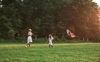 Rural scene. Mother and daughter have fun with kite in the field. Beautiful nature photo