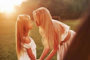 Come on, give me a kiss. Mother and daughter enjoying weekend together by walking outdoors in the field. Beautiful nature photo