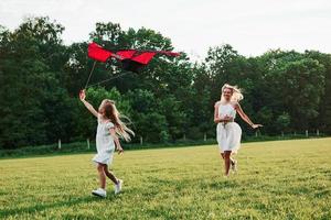 Nice green colors. Mother and daughter have fun with kite in the field. Beautiful nature photo