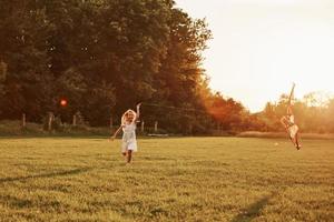 Almost fell. Happy girl in white clothes have fun with kite in the field. Beautiful nature photo