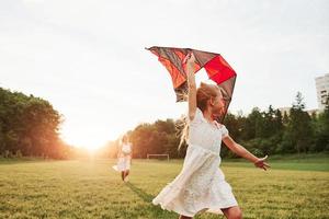 Run like wild. Mother and daughter have fun with kite in the field. Beautiful nature photo