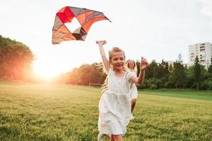 City building behind. Mother and daughter have fun with kite in the field. Beautiful nature photo