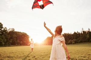 Looking behind. Mother and daughter have fun with kite in the field. Beautiful nature photo