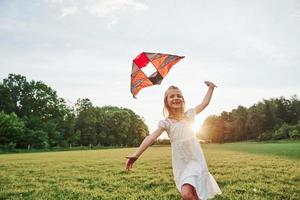 Good mood. Happy girl in white clothes have fun with kite in the field. Beautiful nature photo
