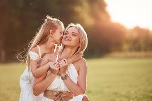 I have secret for you. Mother and daughter enjoying weekend together by walking outdoors in the field. Beautiful nature photo