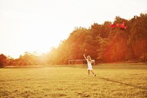 Lots of space to run. Happy girl in white clothes have fun with kite in the field. Beautiful nature photo