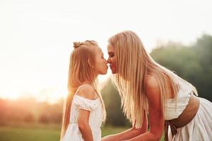 Blurred background. Mother and daughter enjoying weekend together by walking outdoors in the field. Beautiful nature photo