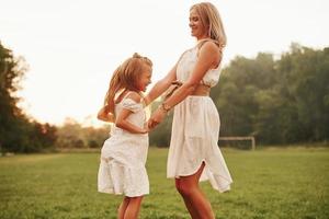 Dancing in a sunlight. Mother and daughter enjoying weekend together by walking outdoors in the field. Beautiful nature photo