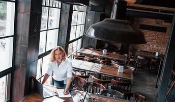 Didn't saw you there. Businesswoman with curly blonde hair indoors in cafe at daytime photo