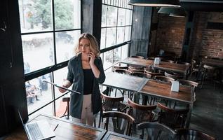 comprobando datos. mujer de negocios con cabello rubio rizado en el interior de la cafetería durante el día foto