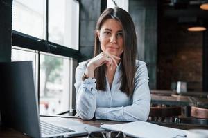 trabajo independiente. mujer de negocios con ropa oficial está adentro en un café durante el día foto