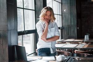 Job almost done. Businesswoman with curly blonde hair indoors in cafe at daytime photo