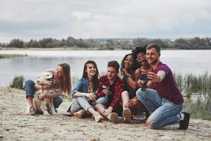 por favor sonríe. grupo de personas hacen picnic en la playa. los amigos se divierten el fin de semana foto